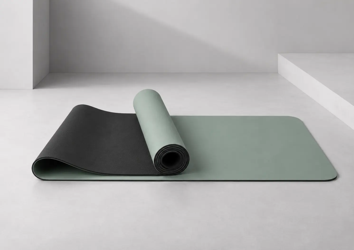 PU and rubber yoga mat with sage green PU top layer and black rubber base shown in a rolled layered structure