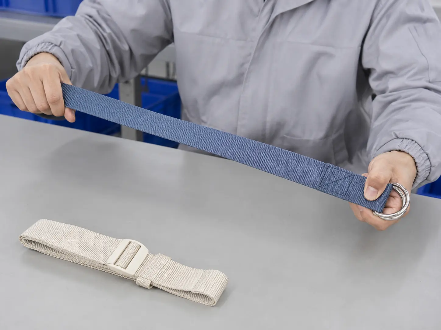 QC staff testing a yoga strap metal D-ring buckle, stitching quality and adjustment function